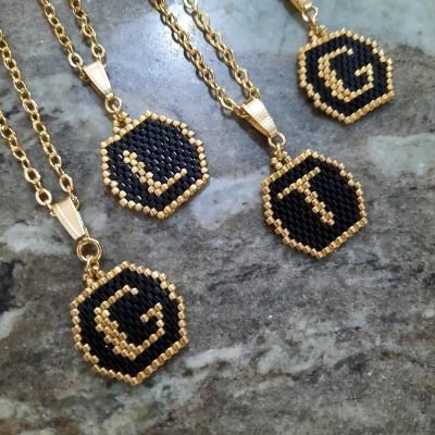 A black and gold letter design necklace by Miyuki beads