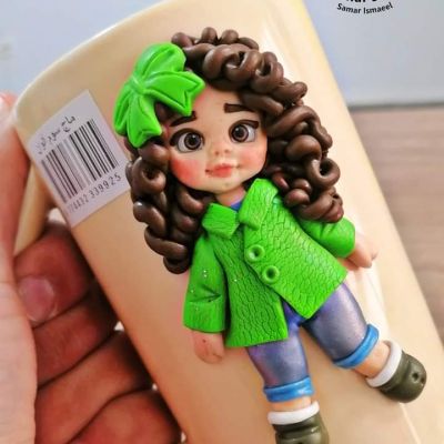 A thermal mug decorated with a doll made of thermal clay